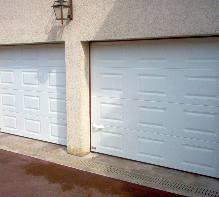 Photo angle d’un habitat cassette avec double porte de garage sectionnelle manuelle blanche en pvc pour les particuliers.
