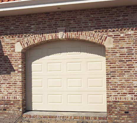 Habitat cassette avec porte de garage sectionnelle crème en pvc installée sur une maison individuelle en brique pour particuliers.