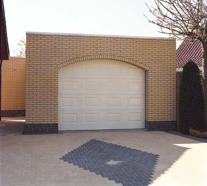 Habitat cassette avec porte de garage sectionnelle blanche en pvc avec contour en brique pour particuliers.