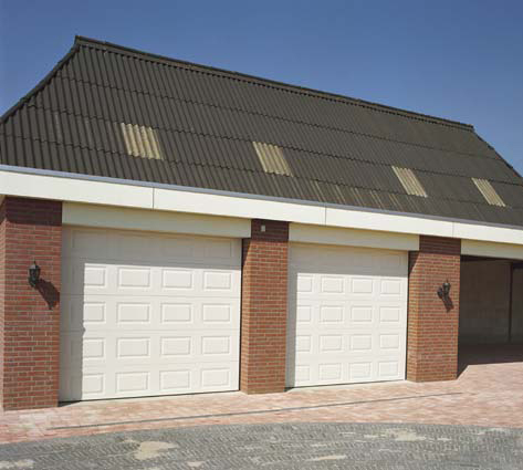 Habitat cassette avec une double porte de garage sectionnelle blanche en pvc avec contour en brique pour particuliers.