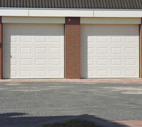 Détail de l’habitat cassette avec double porte de garage sectionnelle blanche en pvc et contours en brique pour particuliers.