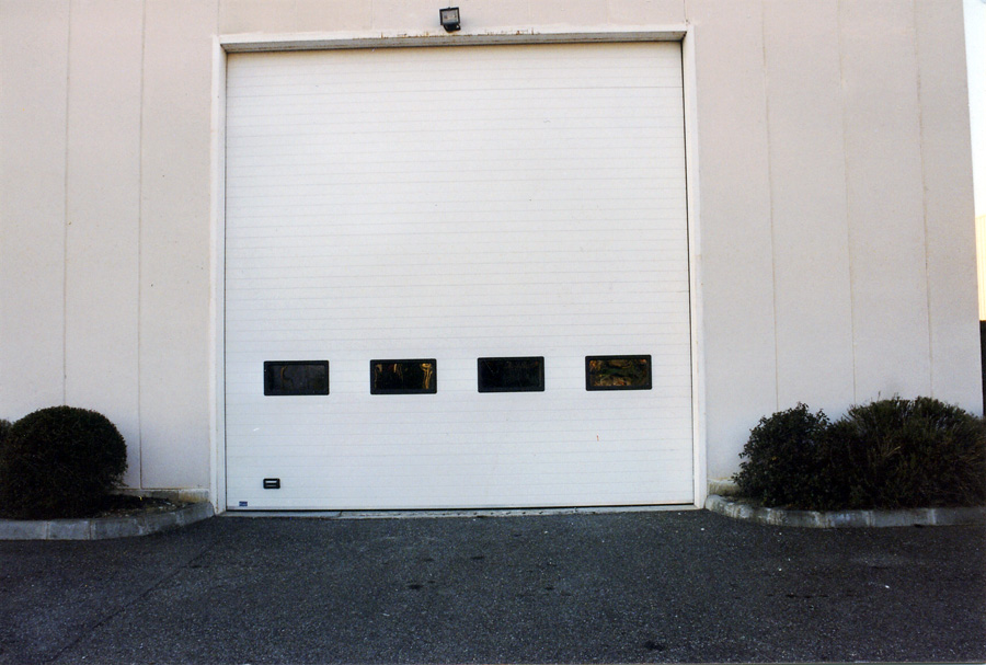 Porte sectionnelle isolée blanche avec quatre vitres pour l’industrie et le commerce.