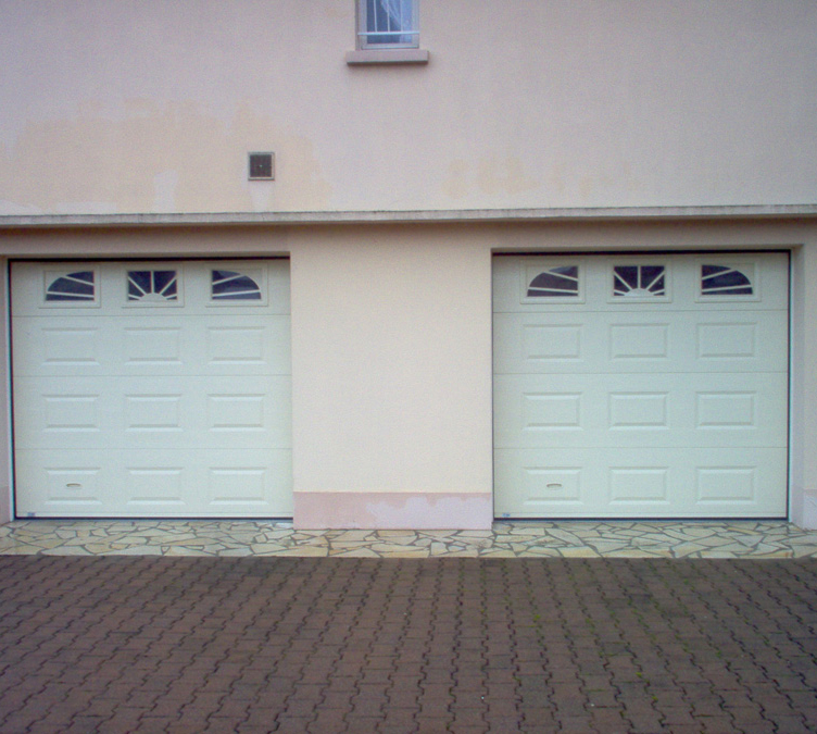 Habitat cassette sur mesure laqué avec double porte de garage sectionnelle blanche et ajourée de trois fenêtres pour les particuliers.
