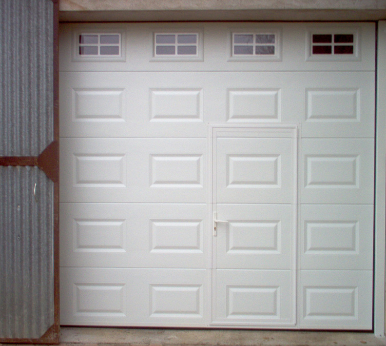 Habitat cassette portillon avec porte de garage sectionnelle blanche en pvc et quatre petites fenêtres ajourées pour les particuliers.