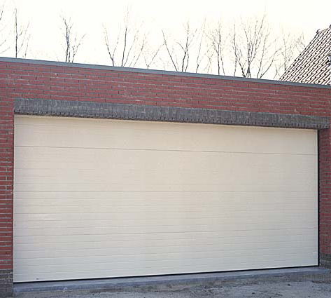 Habitat cassette nervuré avec grande porte de garage sectionnelle blanche et contours en briques.