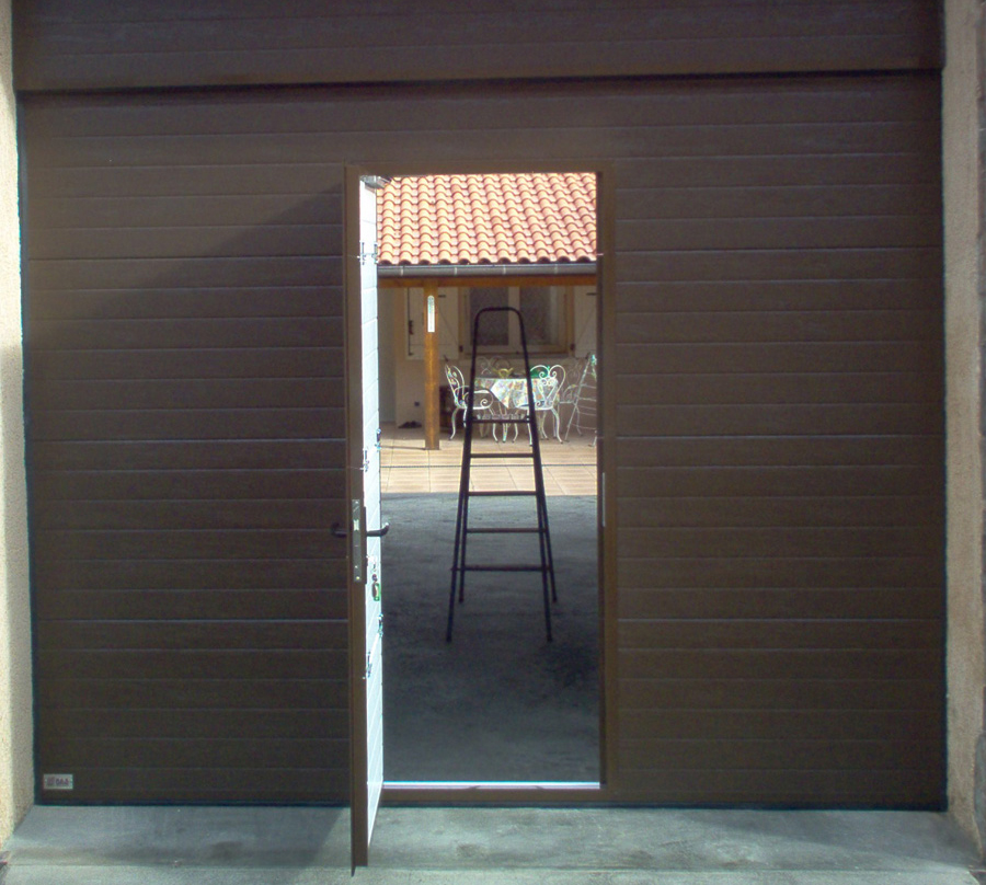 Habitat cassette nervuré à portillon avec porte de garage sectionnelle marron ouverte.