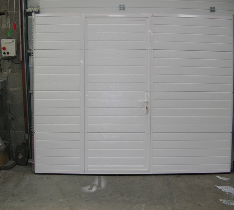 Habitat cassette nervuré à portillon avec porte de garage sectionnelle blanche démontée.